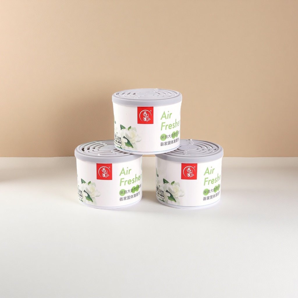 Three cans of white cylindrical solid air freshener with green text, floral patterns, grey LIDS and red brand logo