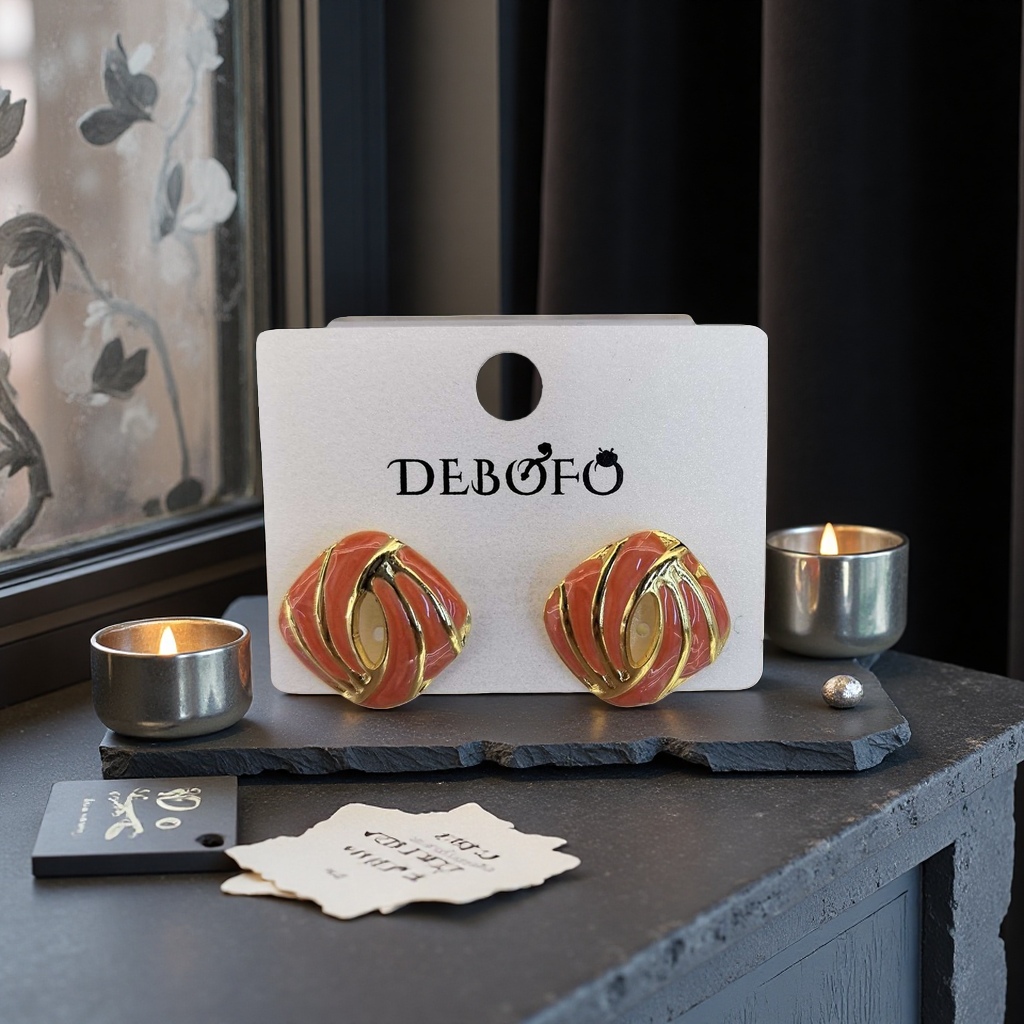 A pair of red and gold alternating smooth line design earrings on a display stand with a gold bracelet