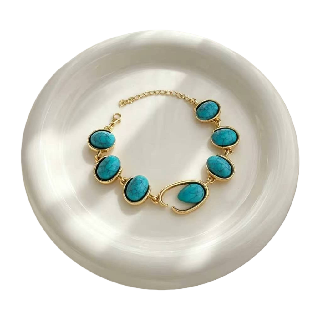 A still life photo display of a golden turquoise bracelet and a white plate Item Picture