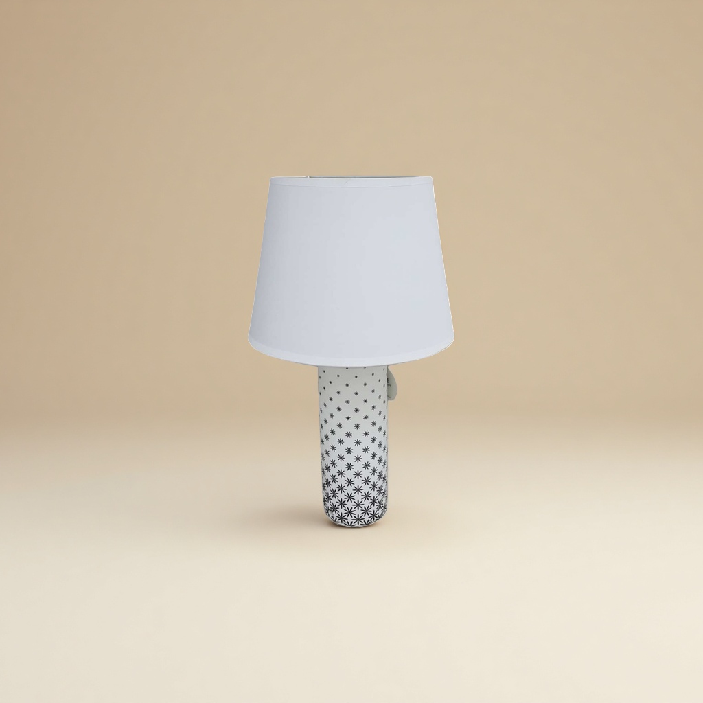 The white lampshade is paired with a black cylindrical lamp base featuring star-shaped patterns