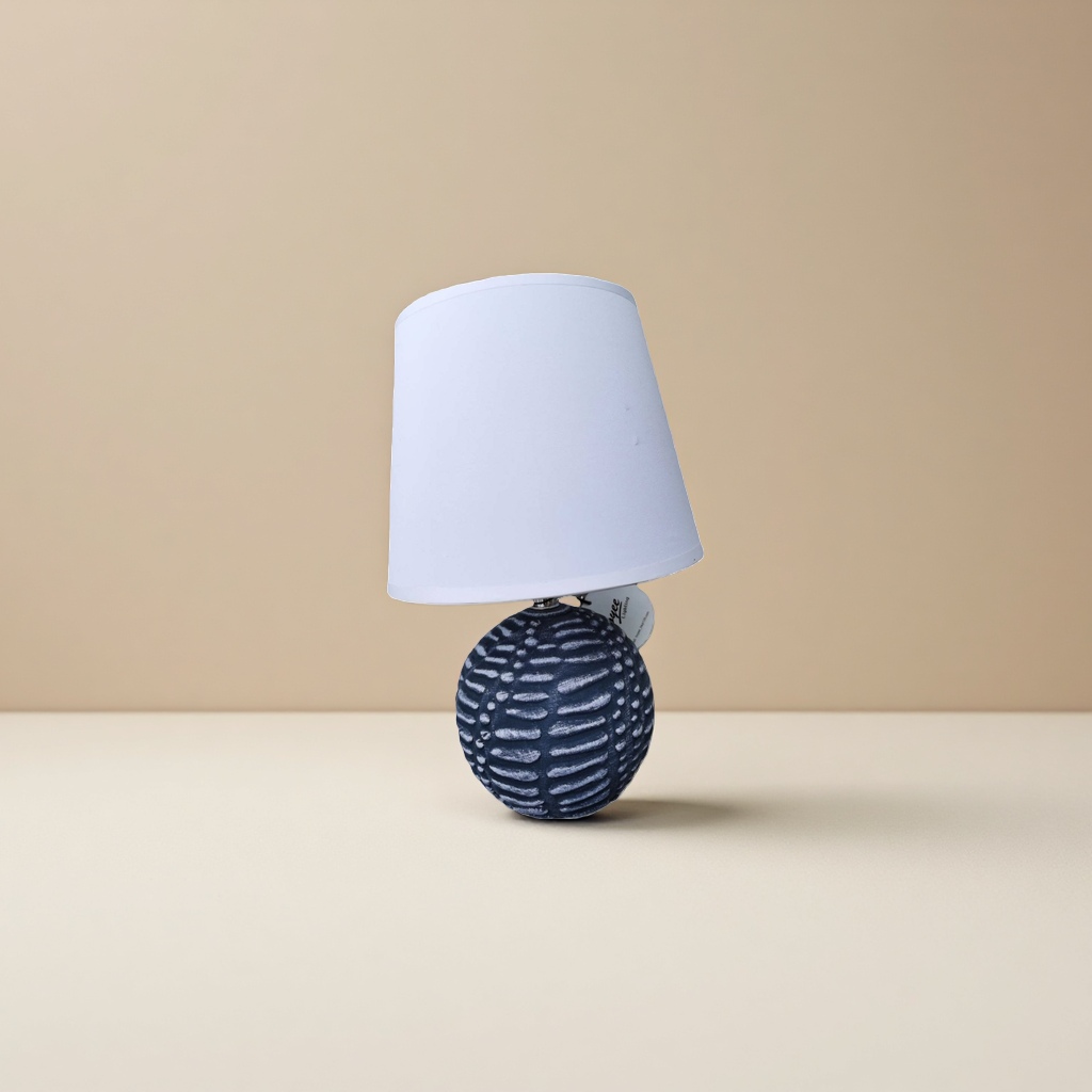 A table lamp with a white lampshade and a deep blue textured spherical base