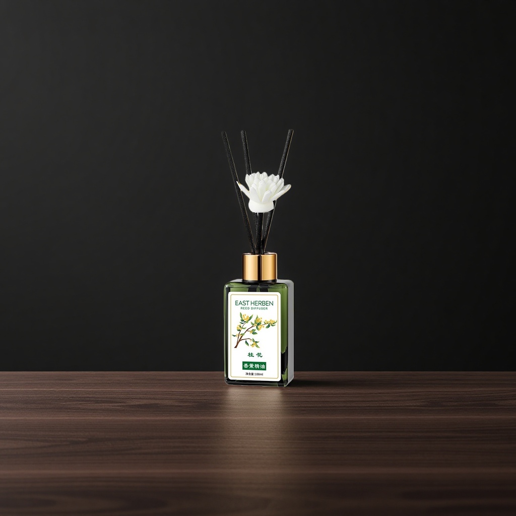 绿色玻璃瓶装香薰精油+黑色香薰棒，瓶身贴有“EAST HERBEN REED DIFFUSER”标签，配白色莲花造型装饰，背景为桂花枝叶特写。细节图