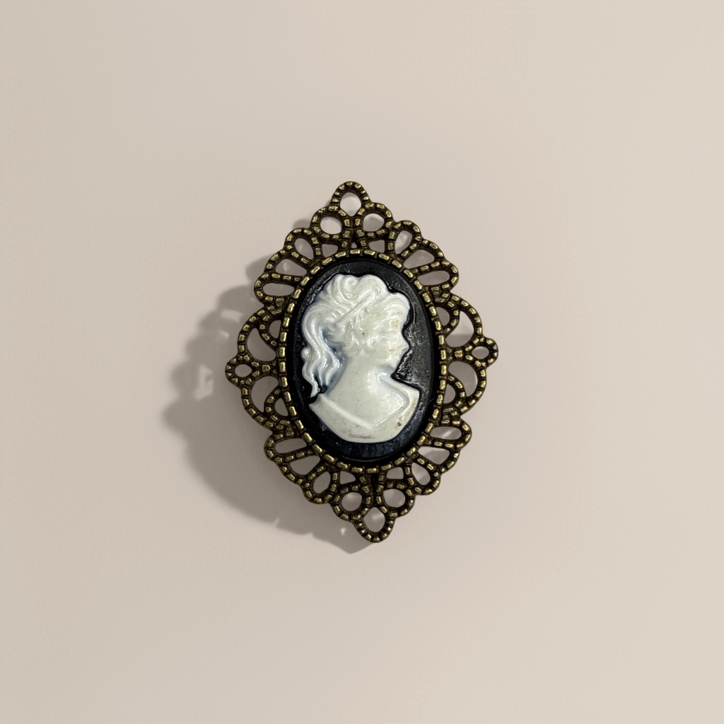A retro brooch with a golden hollowed-out frame, black background and white embossed female profile