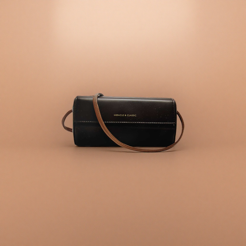 A black leather crossbody bag with a brown shoulder strap and golden MIRACLE & CLASSIC letches on the front Application Scenario
