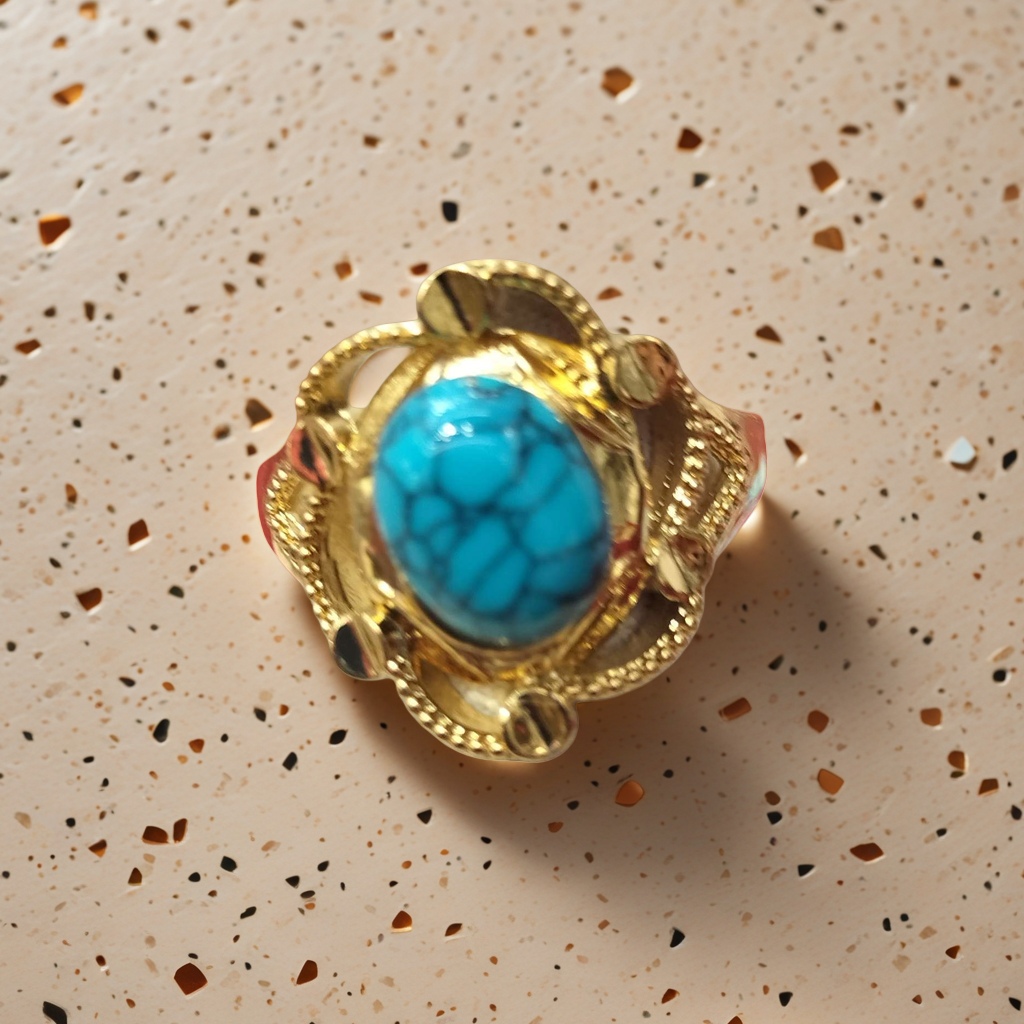 A simple and fashionable women's accessory with a golden ring and a natural turquoise gemstone in blue-green color