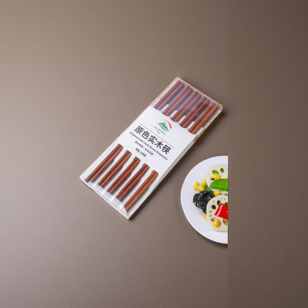 透明包装盒装的原色实木筷子，置于木质砧板旁，右下角有盛放蔬菜的白盘细节图