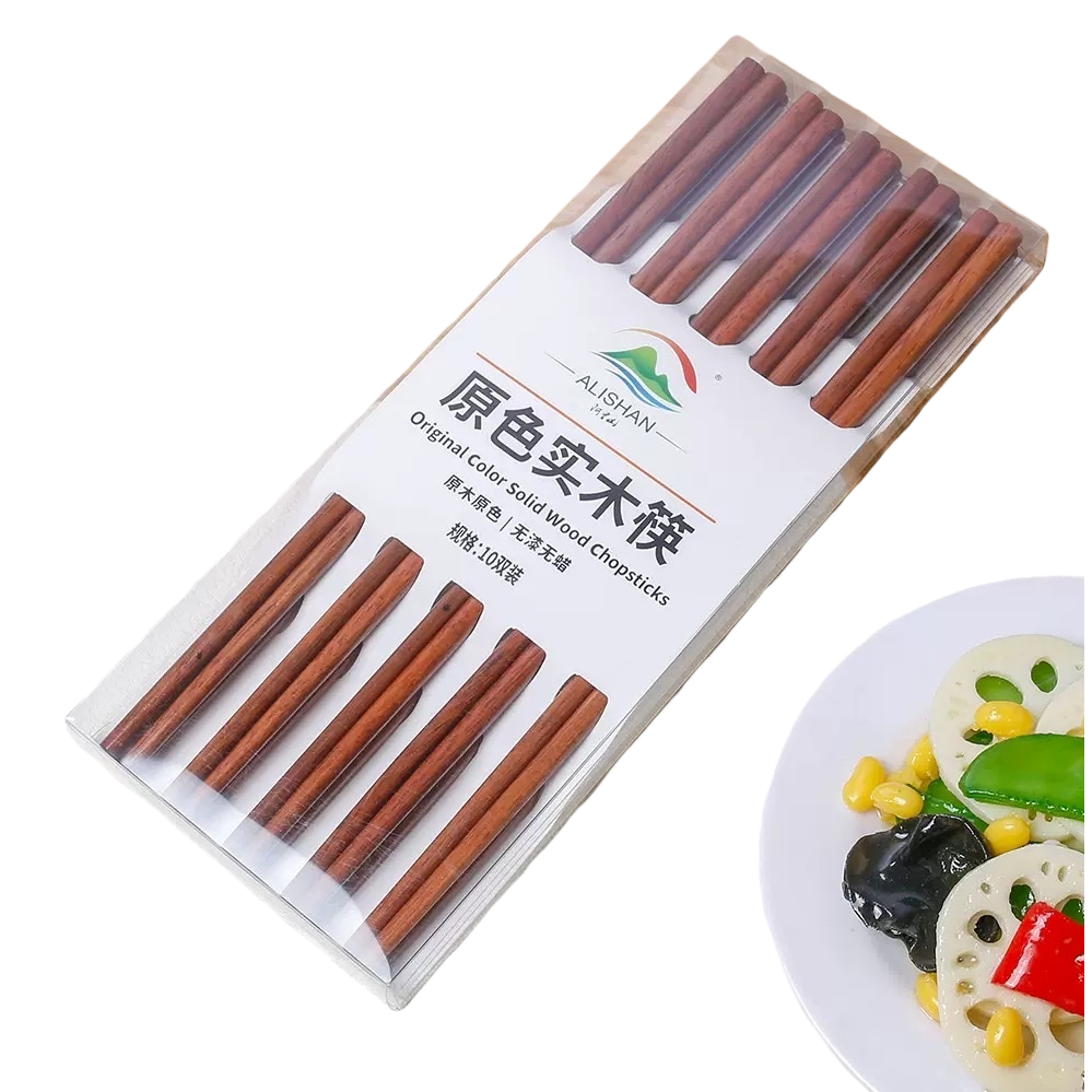 透明包装盒装的原色实木筷子，置于木质砧板旁，右下角有盛放蔬菜的白盘白底实物图