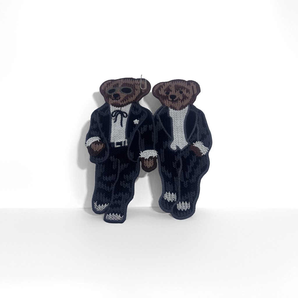 Knitted and embroidered bear brooch, dark blue suit, brown bear with white high collar, holding a plush cup, white serrated bottom