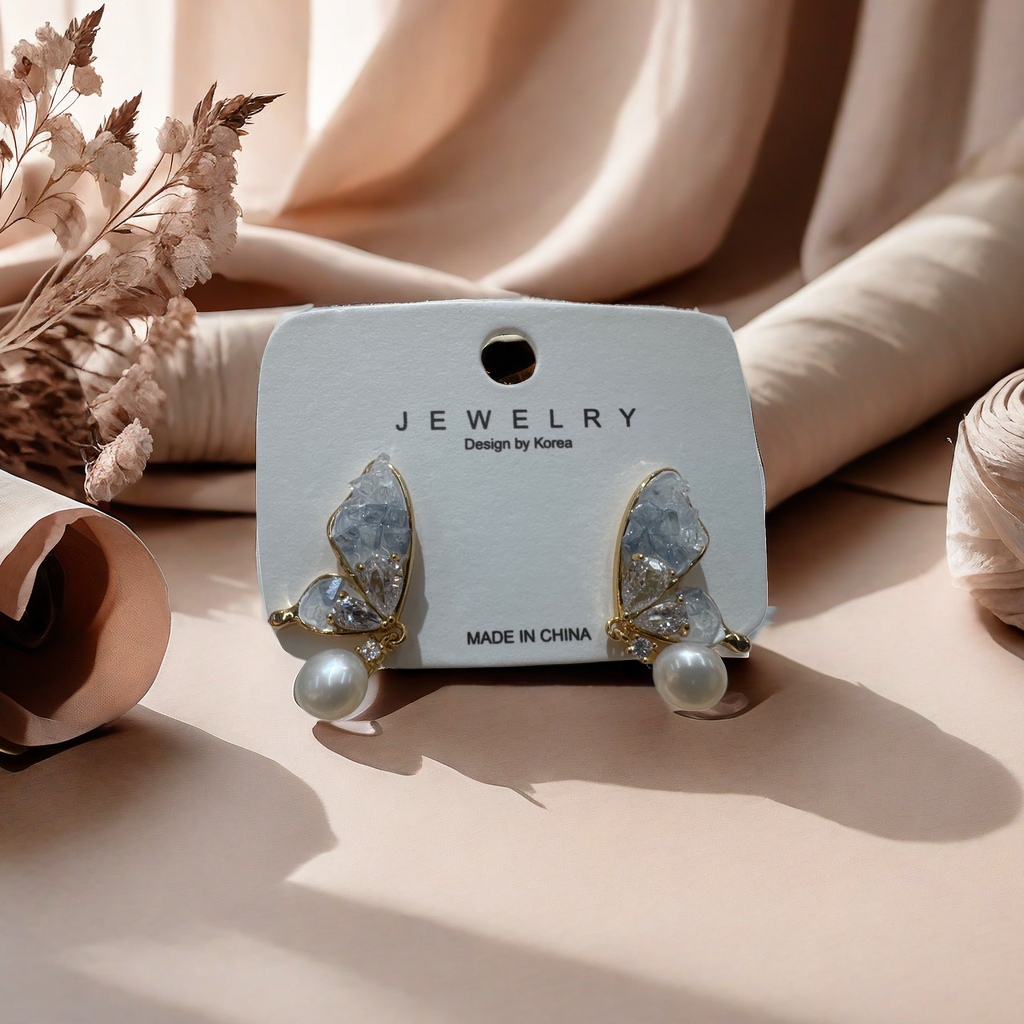 Golden butterfly-shaped stud earrings are inlaid with transparent crystals and pearls and come with white labels