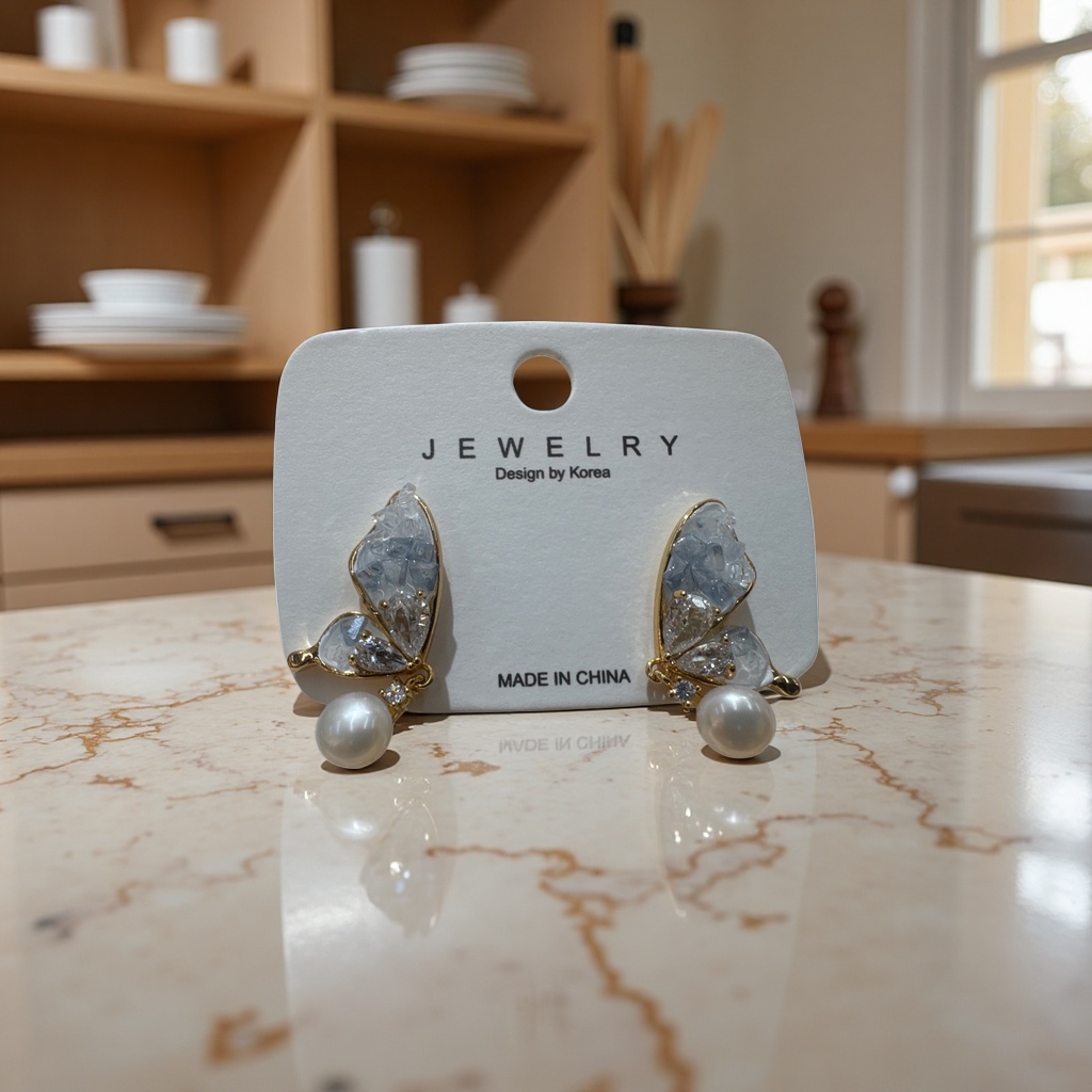 Golden butterfly-shaped stud earrings are inlaid with transparent crystals and pearls and come with white labels details Picture