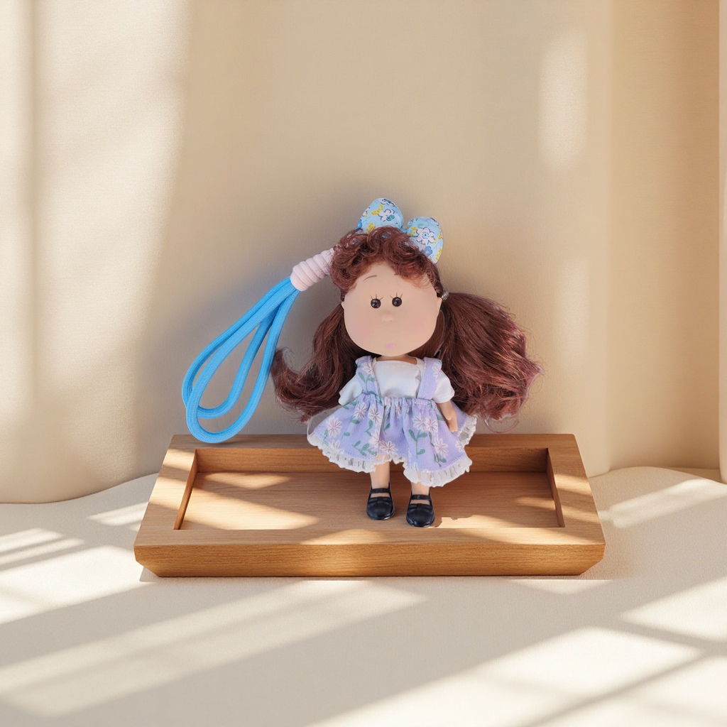 Brown curly doll, purple floral dress, black leather shoes, blue and white floral bow, grey wood grain background