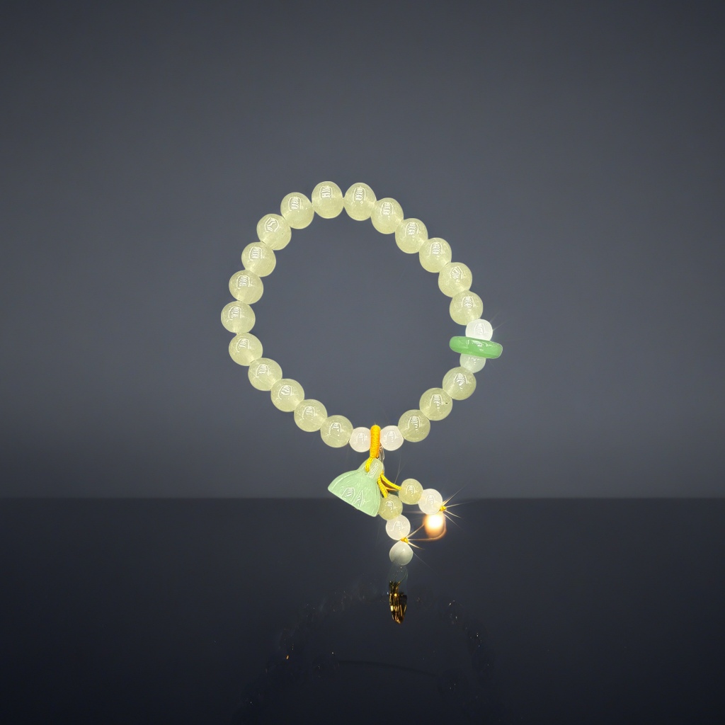 A light green glass bead bracelet with a lotus pendant, a green jade pendant and a yellow rope knot lead all the way