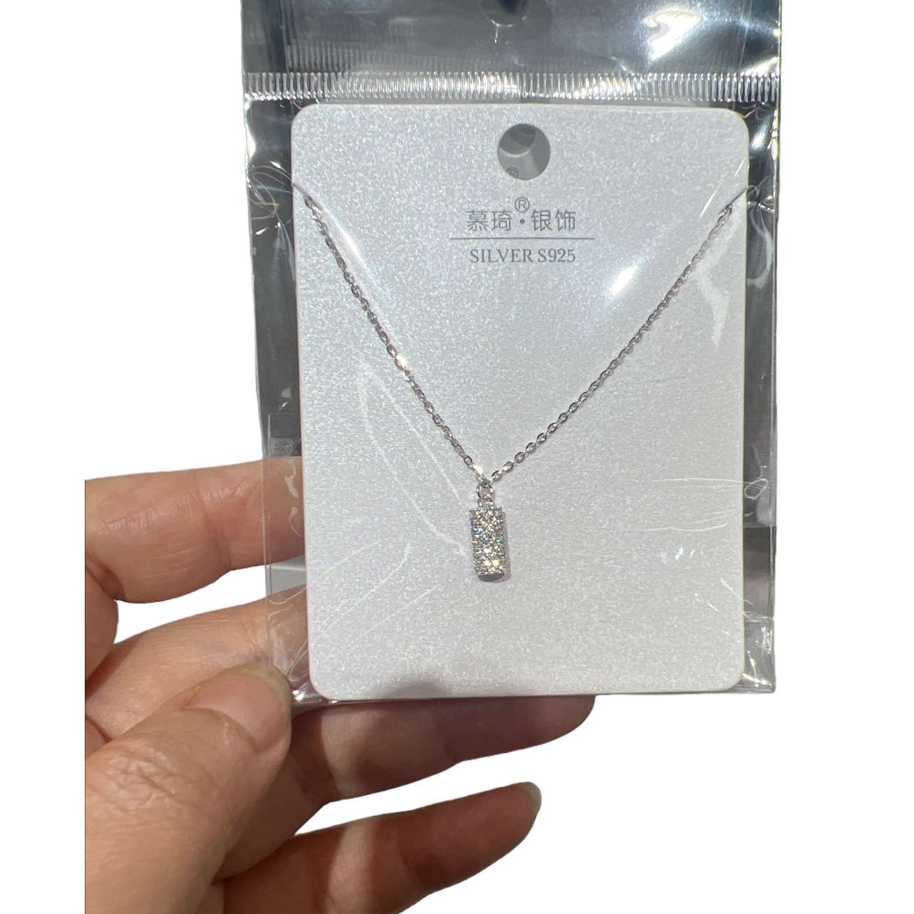 A silver full diamond rectangular pendant necklace with a fine chain, supported by white glitter cardstock for display, and packaged in transparent plastic Item Picture