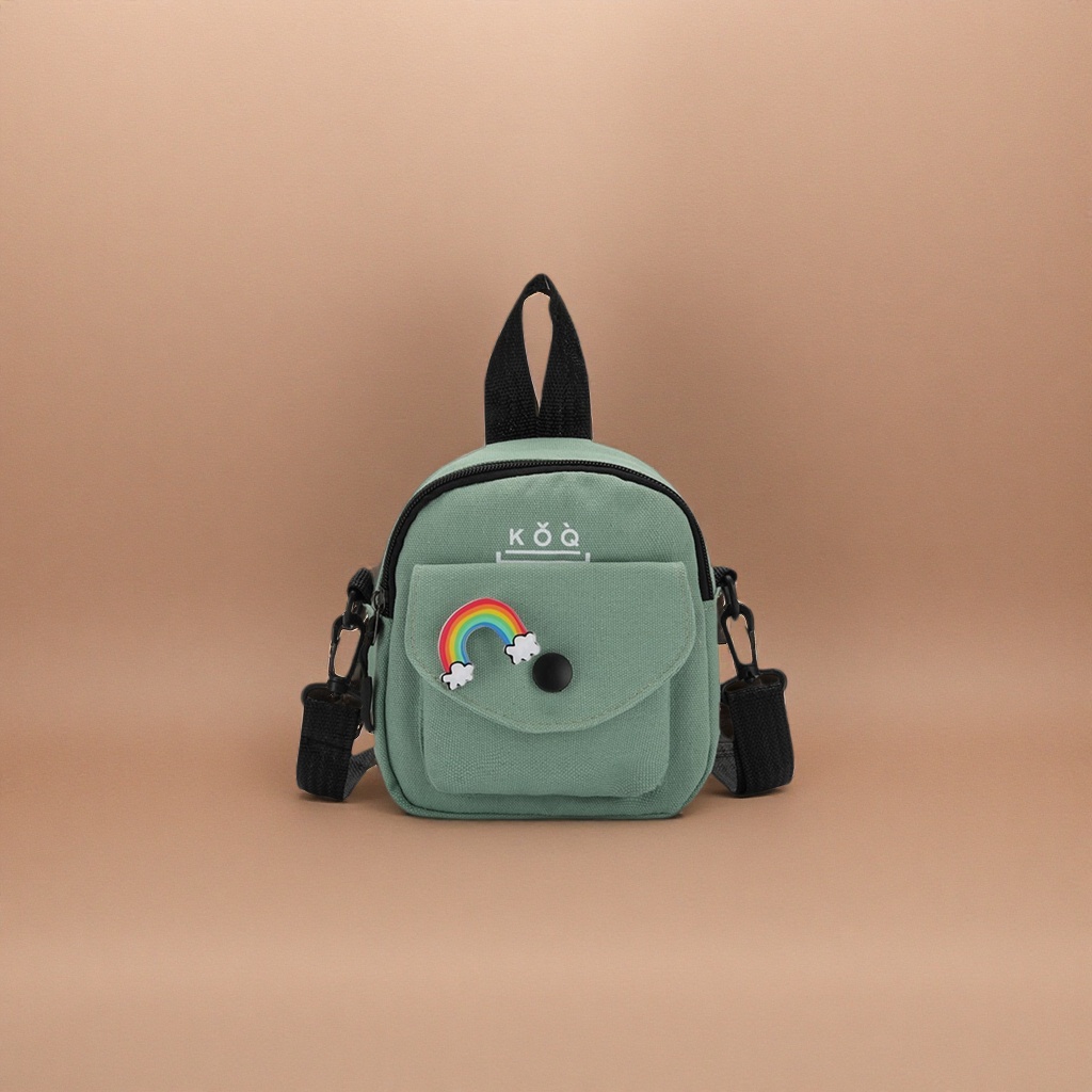 The green canvas small backpack has a rainbow cloud badge on the front, a black snap button and a black shoulder strap handle