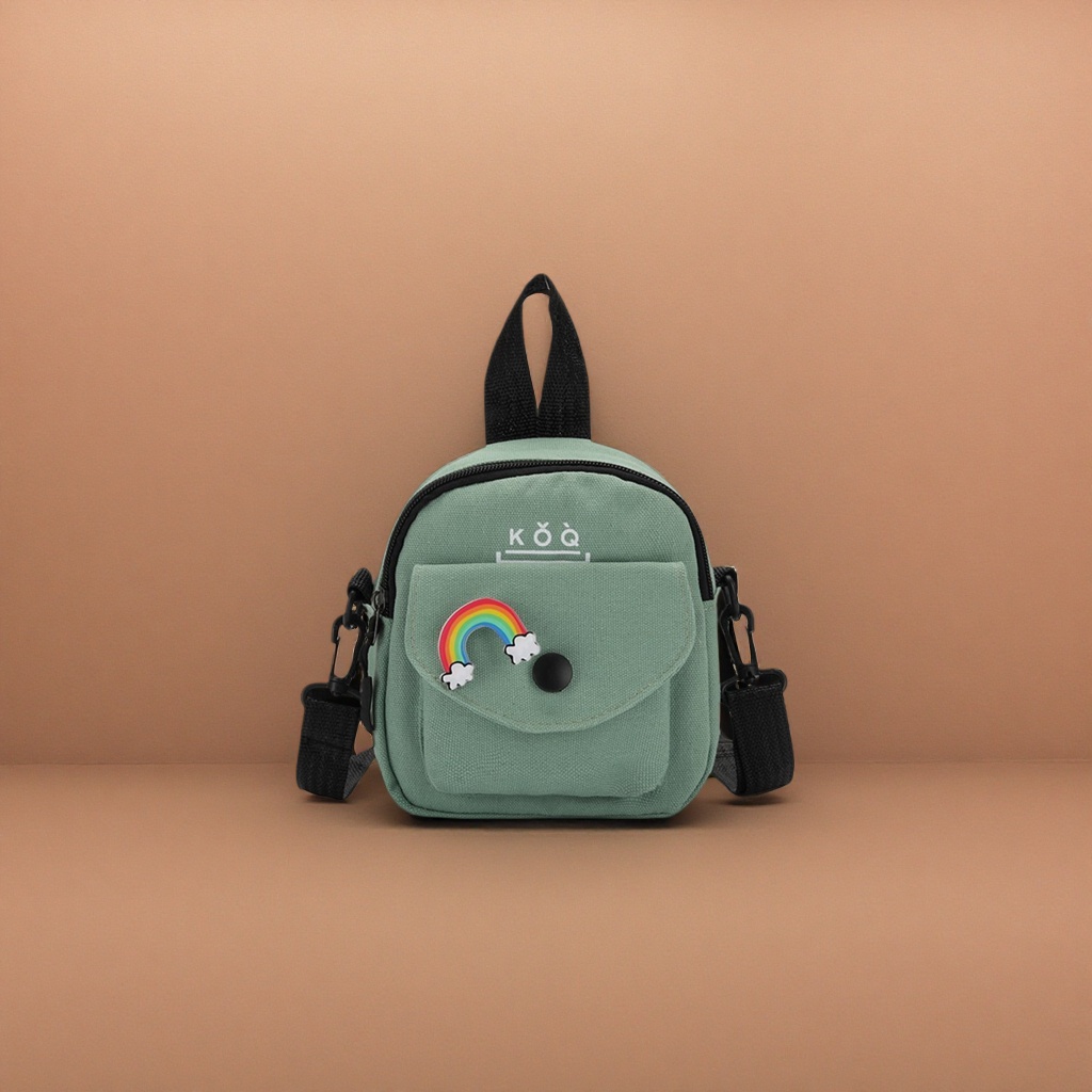 The green canvas small backpack has a rainbow cloud badge on the front, a black snap button and a black shoulder strap handle details Picture
