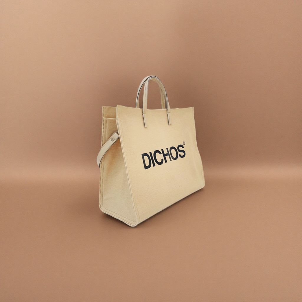 The front of the beige canvas tote bag is printed with the black word "DICHOS"