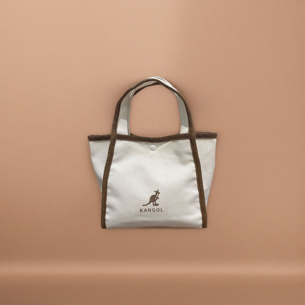 The off-white canvas handbag is decorated with a kangaroo pattern and the KANGOL logo on a brown webbing