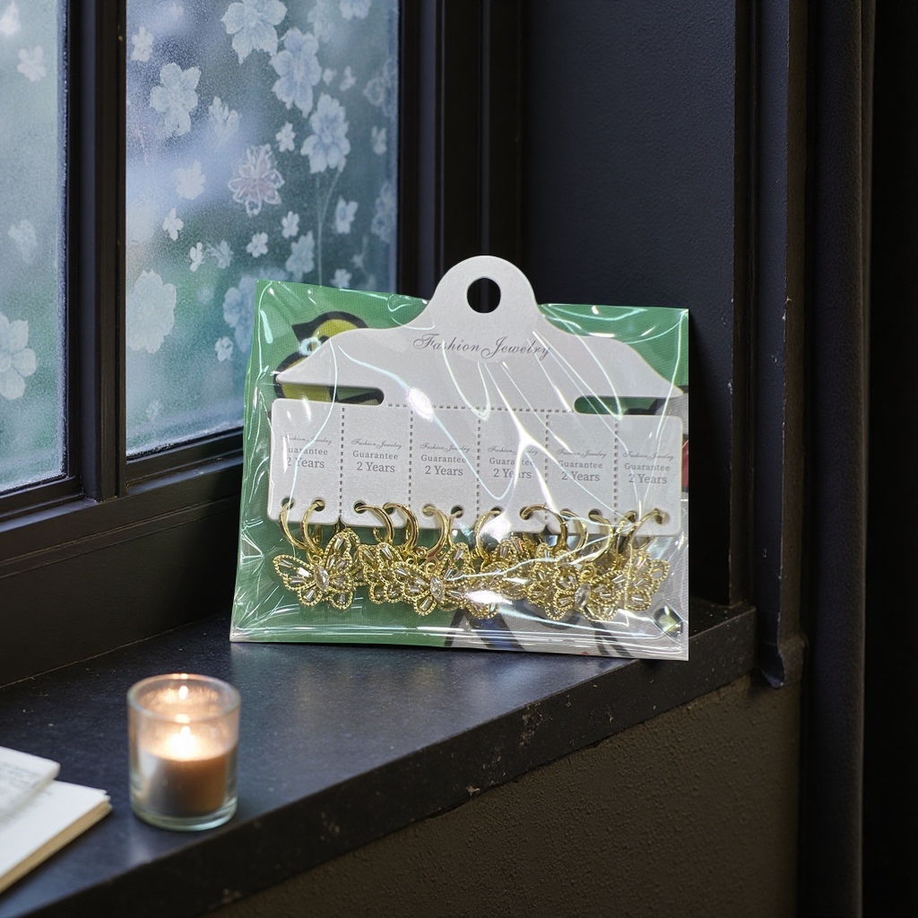 Golden butterfly-shaped earrings, packaged in a transparent plastic bag, with a white tag and a green cartoon fabric background Specification image