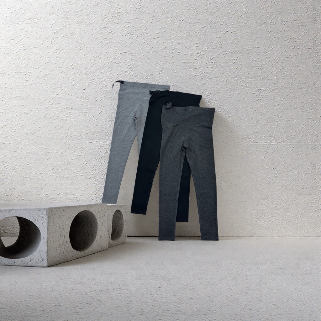 A grey hooded sweatshirt paired with black trousers is displayed on a wooden textured tabletop details Picture