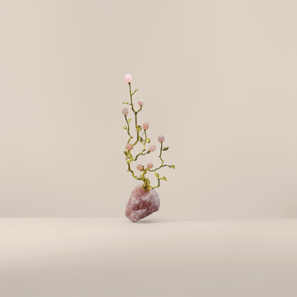 A pink gemstone ornament inlaid with golden branches and a rose quartz base