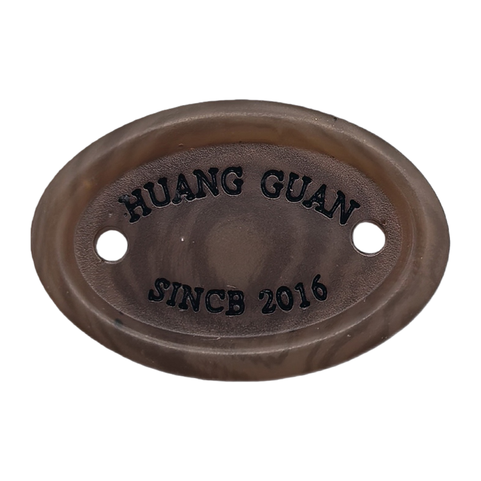 棕色椭圆形金属铭牌，表面刻有“HUANG GUAN”和“SINCB 2016”字样，两侧各有一个圆孔白底实物图