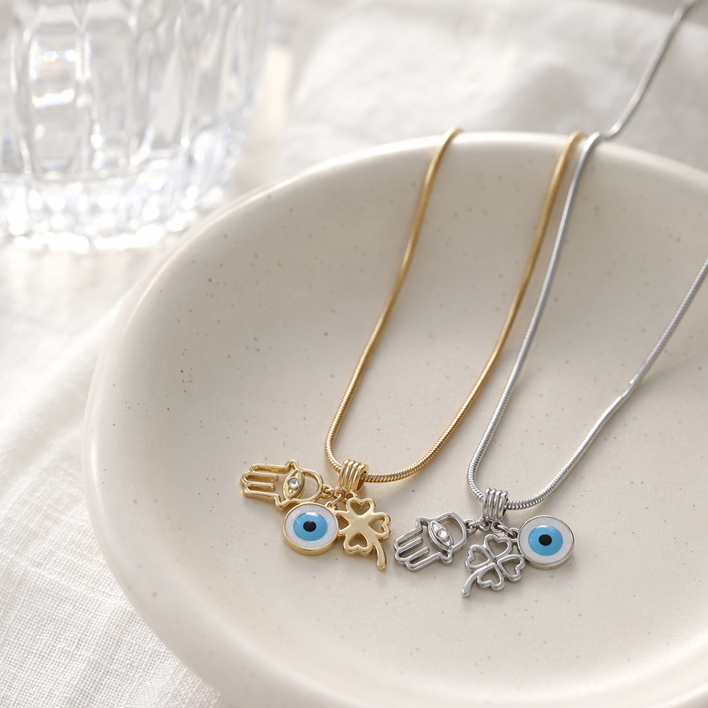 A silver and gold snake bone chain necklace with Fatima's hand and a blue eye four-leaf clover pendant details Picture