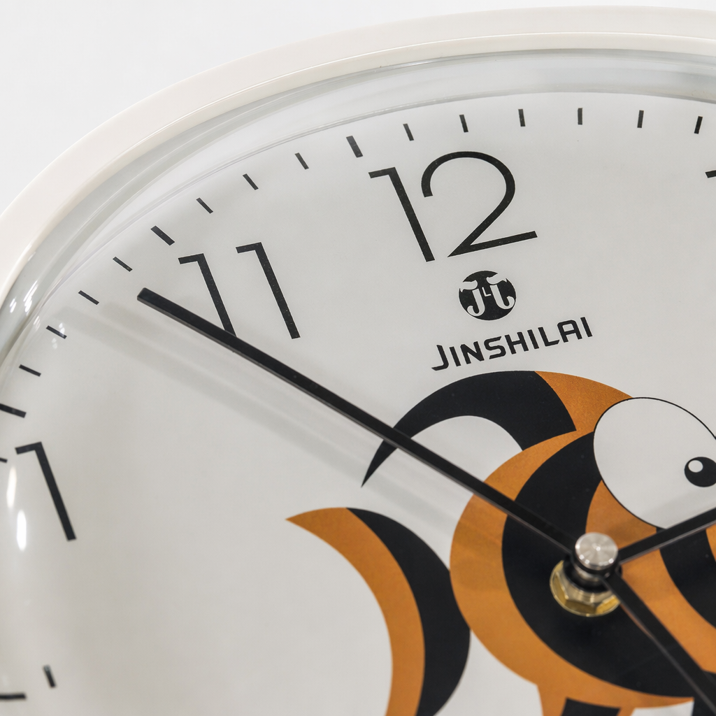 The Jinshilai silent quartz white round wall clock has an orange and black cartoon fish pattern hand in the center of the dial at 10:13 Application Scenario