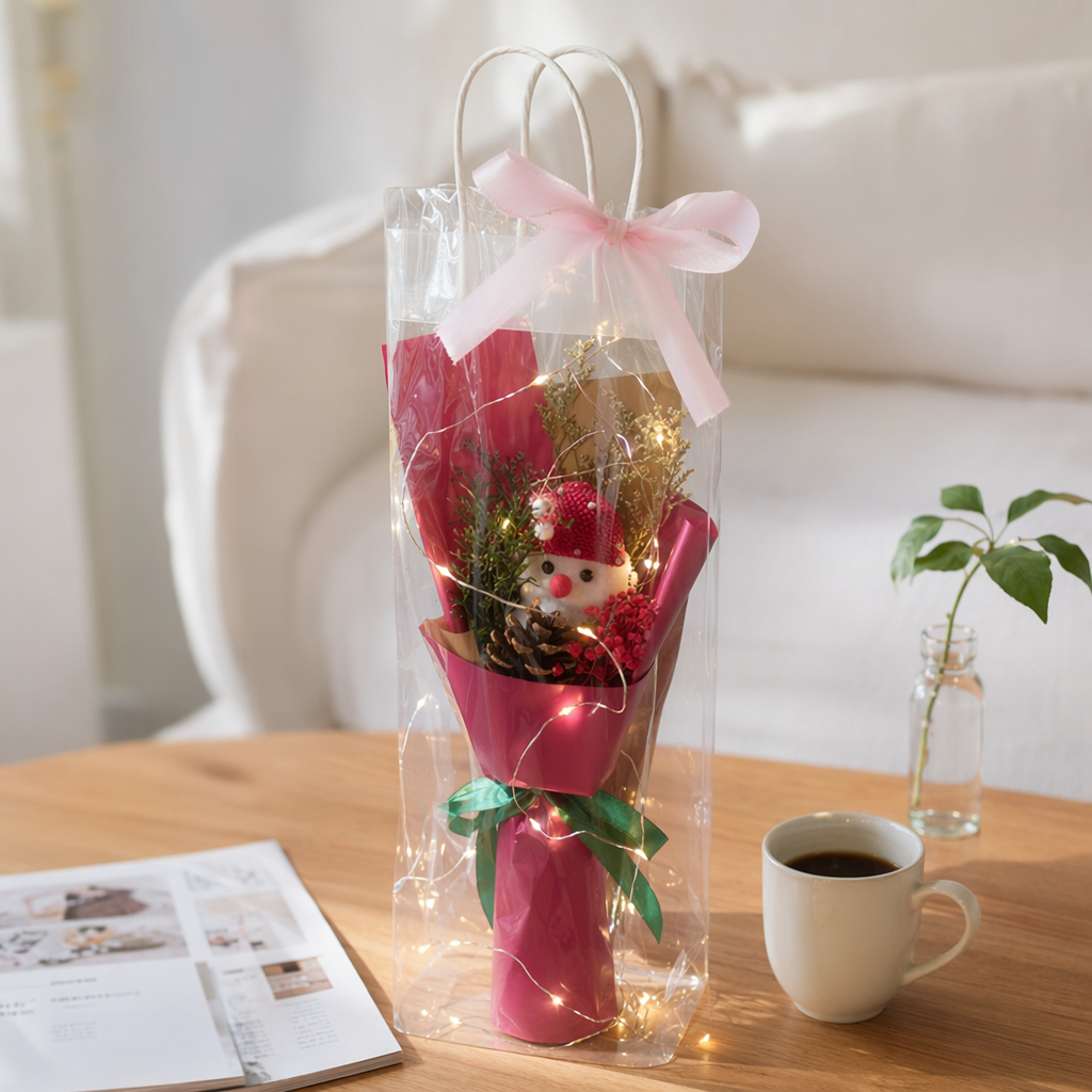 Pink packaged bouquet with snowman doll, pinecone, red berries, dried flowers, transparent bag, green ribbon and warm-colored string of lights details Picture