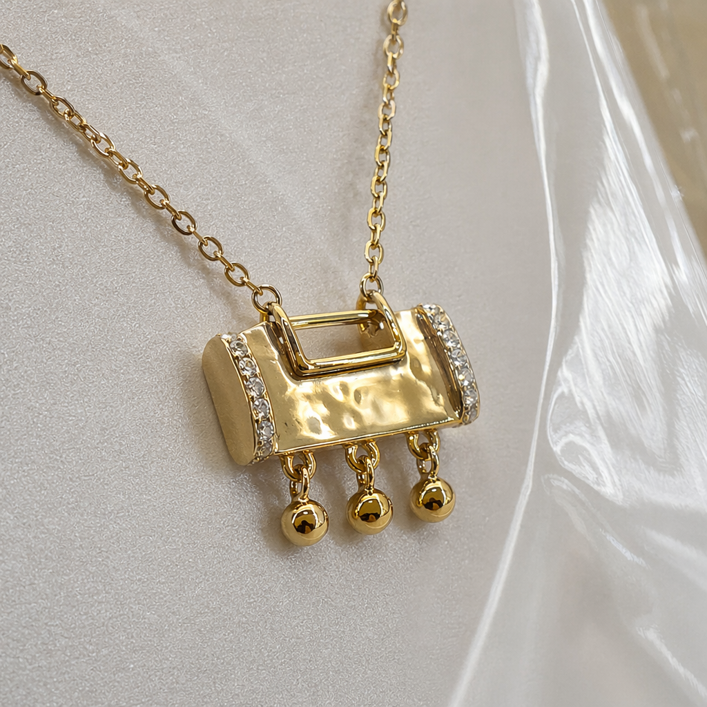 A golden rectangular small bell pendant necklace, held in a transparent bag with a white card Application Scenario