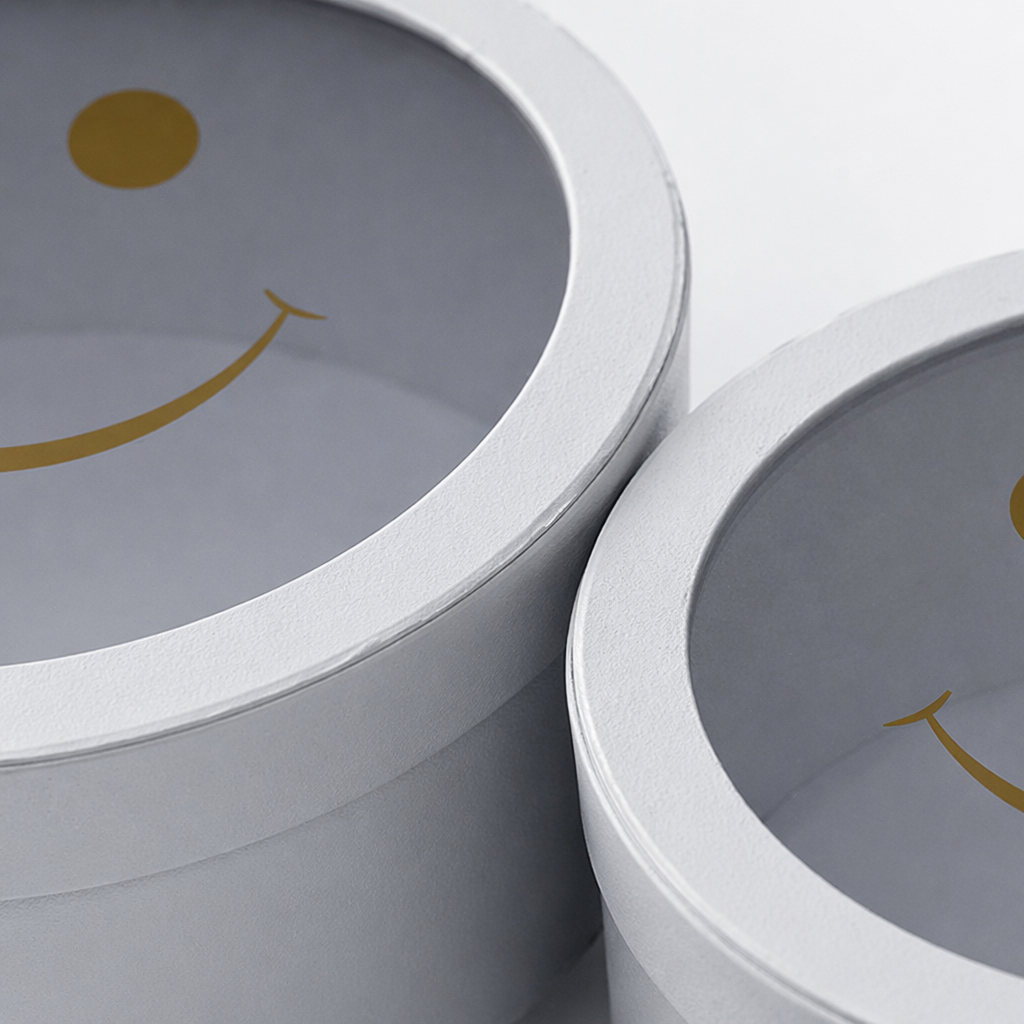 A white circular gift box with a transparent lid and a golden smiling face pattern Application Scenario