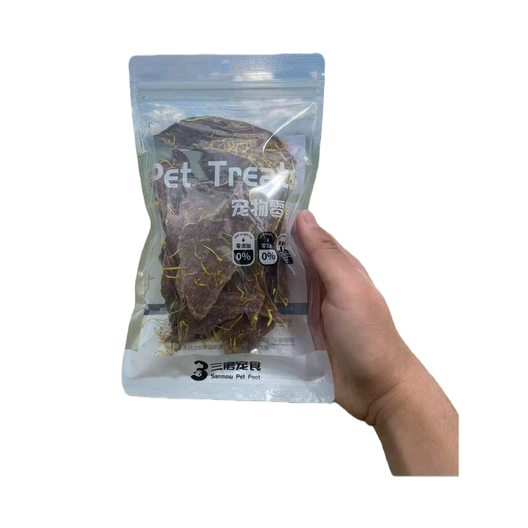 Holding a transparent bag of pet snacks, dark brown dried meat with yellow crumbs, green grass and a blue sky background Item Picture