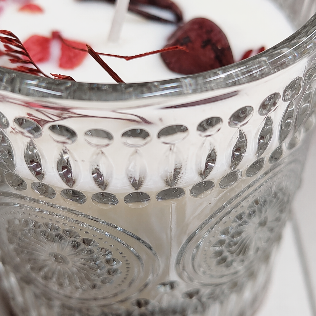 A transparent glass cup is filled with white candles and dark red petal decorations Application Scenario