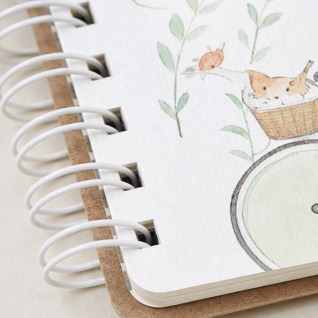 The cover of the white spiral-bound notebook is printed with the words "HAPPY RIDING" and the illustration of a girl riding a bike with a cat Application Scenario