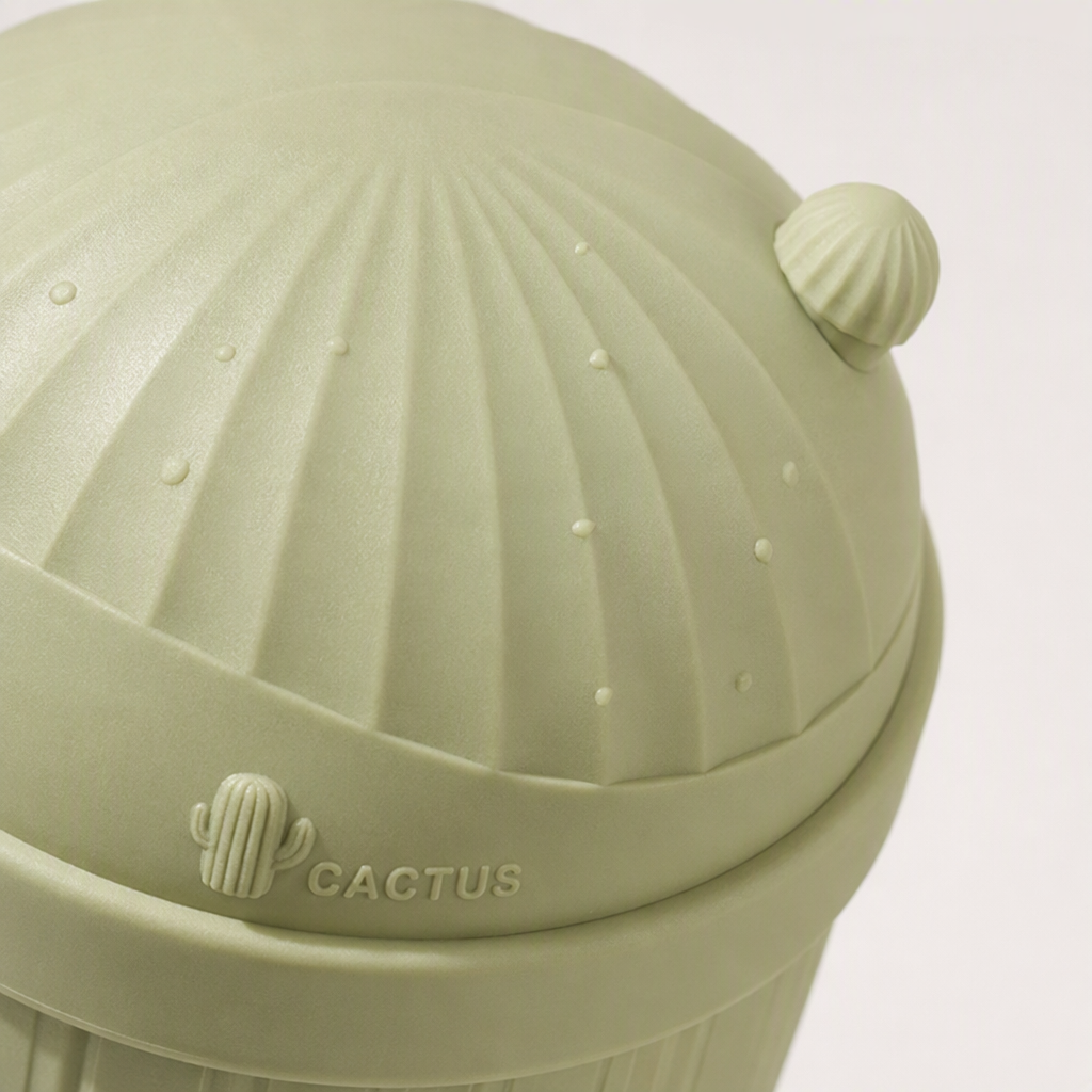 The creative three-color cactus flip lid trash can is green, off-white and light yellow. It is environmentally friendly and practical for home storage, placed on a checkered tablecloth Application Scenario