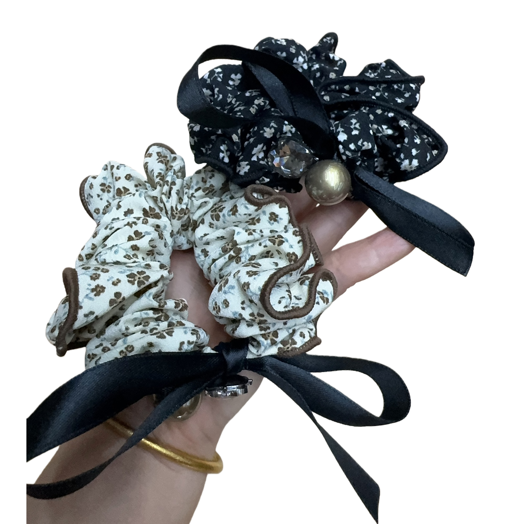 Black floral hair tie with pearl decoration, beige and brown floral hair tie, black ribbon, held on a wooden tray for display Item Picture