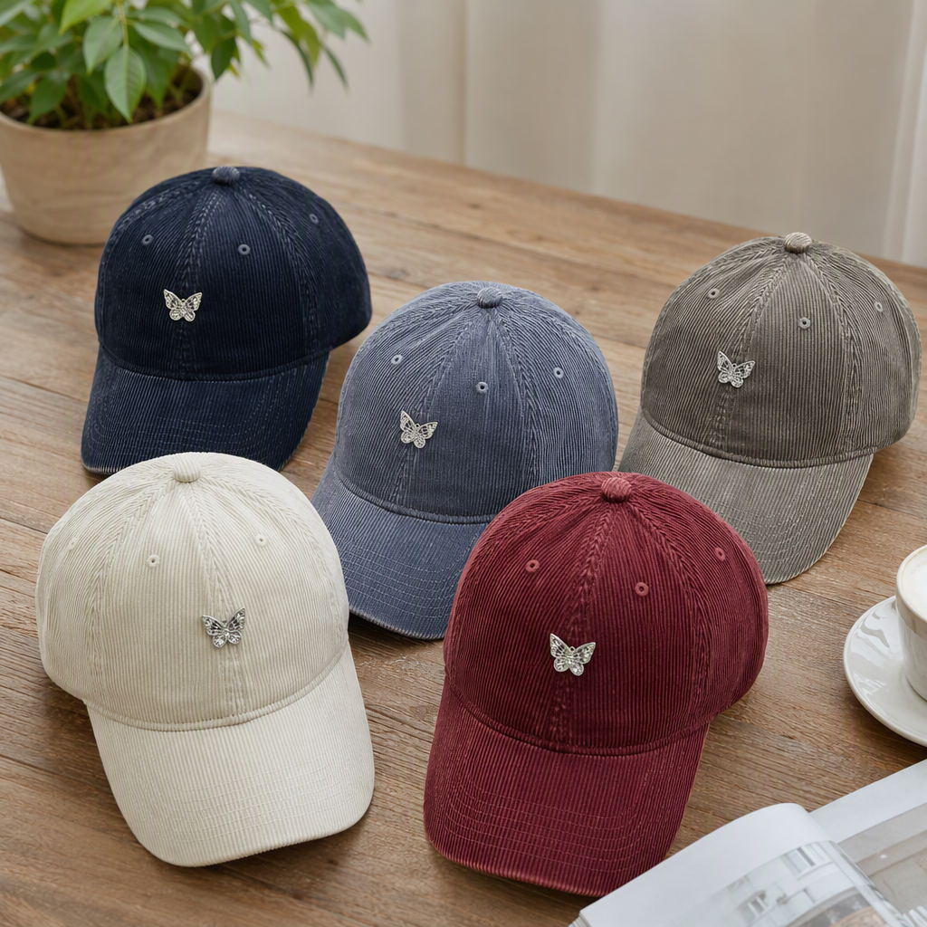 Five colorful corduroy baseball caps, silver butterfly badges, casual and trendy men's and women's designs, and a light grey wood grain floor are on display details Picture
