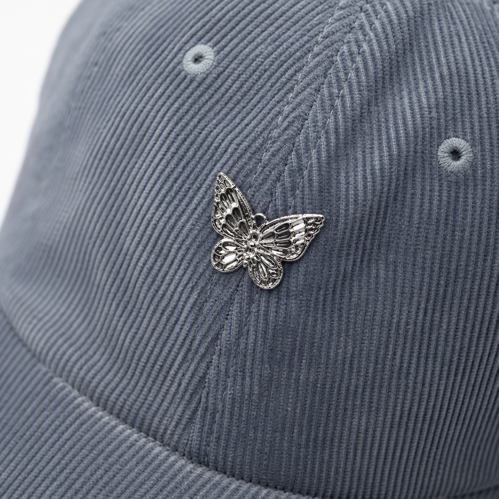 Five colorful corduroy baseball caps, silver butterfly badges, casual and trendy men's and women's designs, and a light grey wood grain floor are on display Application Scenario