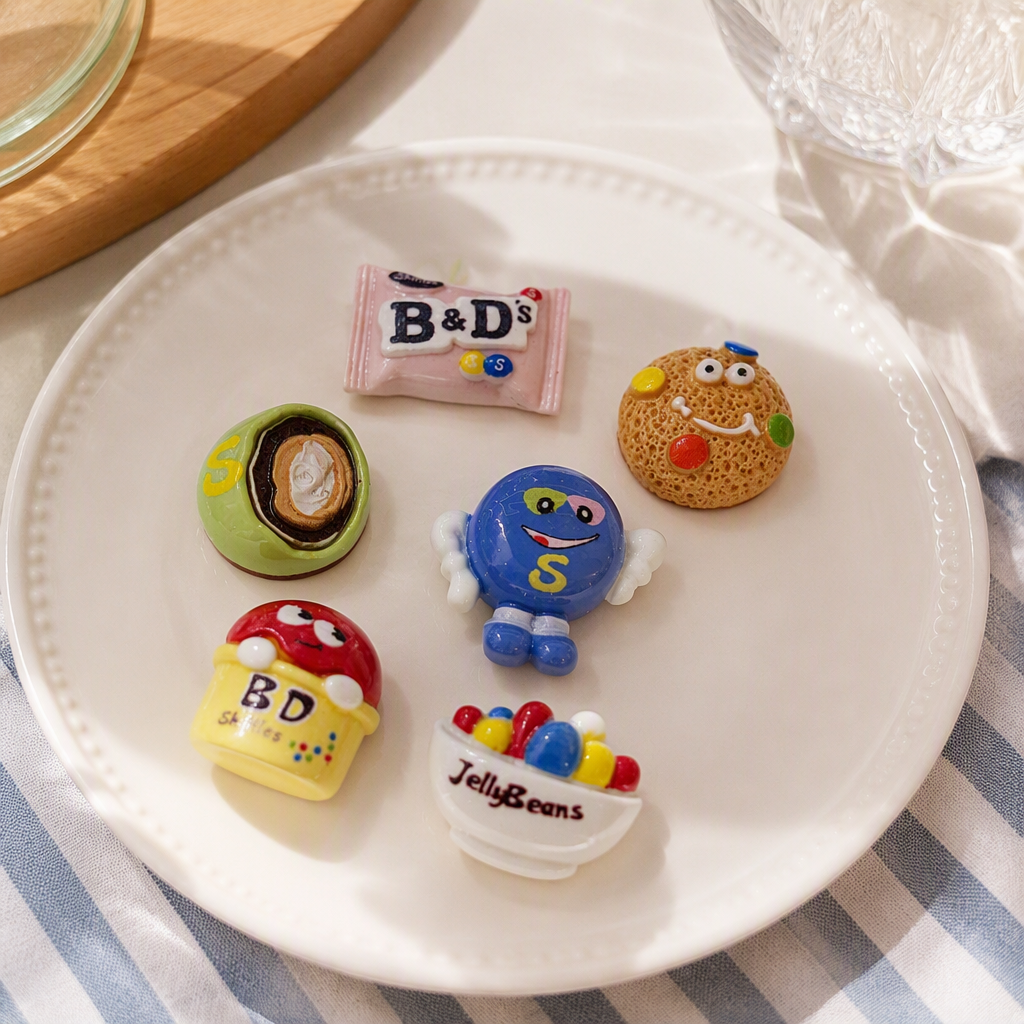 Six colorful candy-themed tiles with a pink background, B&D's chocolate cookie face, S-shaped egg roll, Smurfs, Jelly Beans, BD Skittles rainbow details Picture