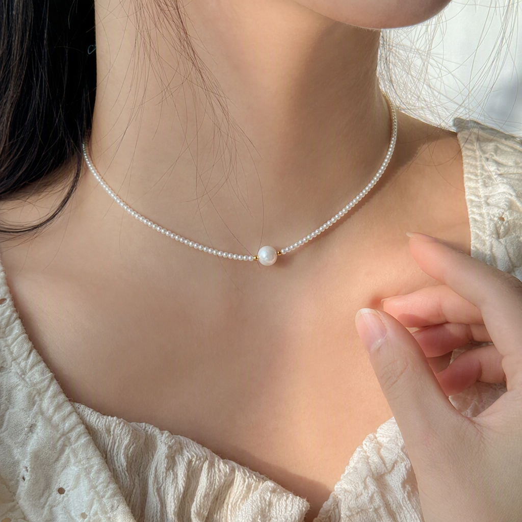 The white pearl necklace is delicately strung with a large, round pearl in the center. It features a golden clasp and a heart-shaped pendant, making it an elegant accessory details Picture