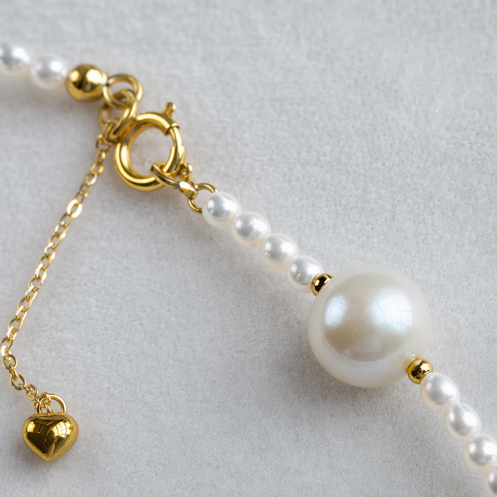 The white pearl necklace is delicately strung with a large, round pearl in the center. It features a golden clasp and a heart-shaped pendant, making it an elegant accessory Application Scenario