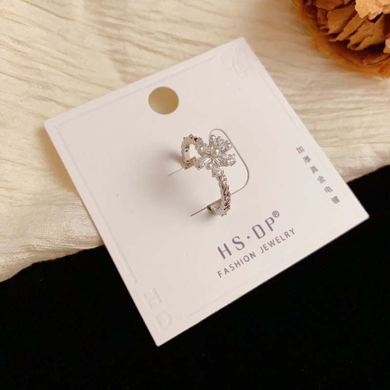 A Japanese and Korean niche diamond-encrusted pearl flower ring with an ins light luxury and high-end feel, simple and cold style. A woman who wears the ring with her mouth open details Picture