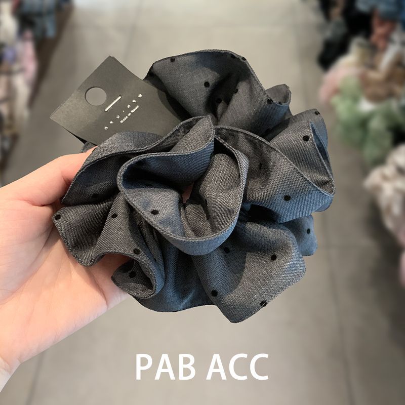 A Korean-style pleated polka dot large intestine hair band with a laid-back and high-end look. It features a super large bun with a ponytail and a leather band hair tie