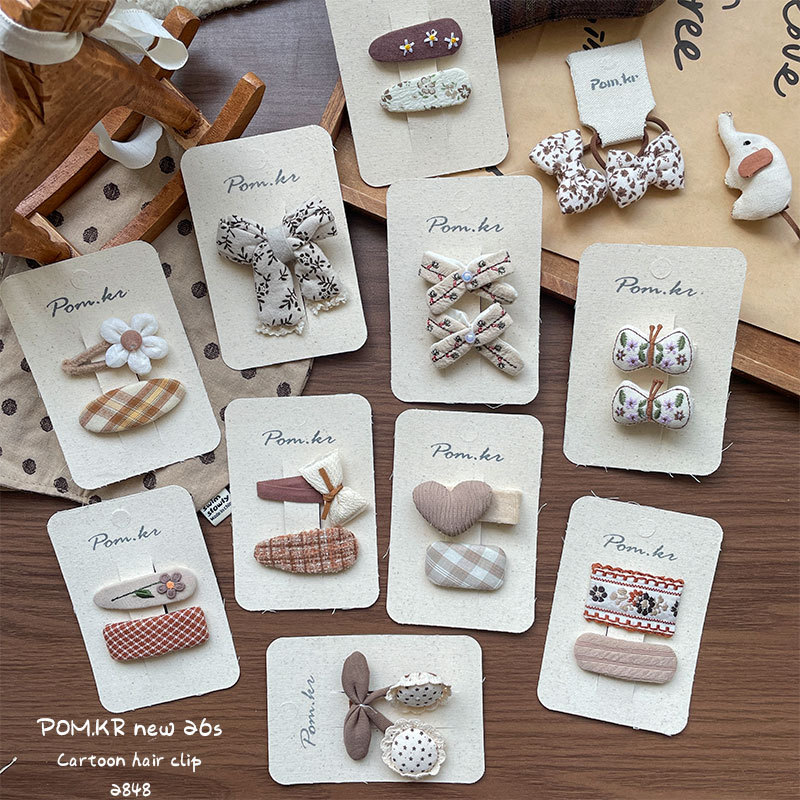 New Korean-style fabric coffee-colored handcrafted hair accessory for children, featuring a bow with floral patterns on the side and a duck clip for baby hair