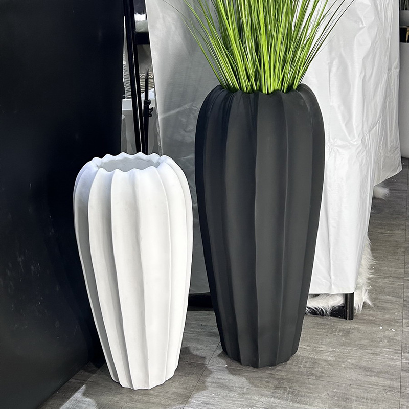 A large floor-standing plant arrangement in a minimalist style beside the sofa in the living room, featuring a new matte black and white bright color vase Specification image