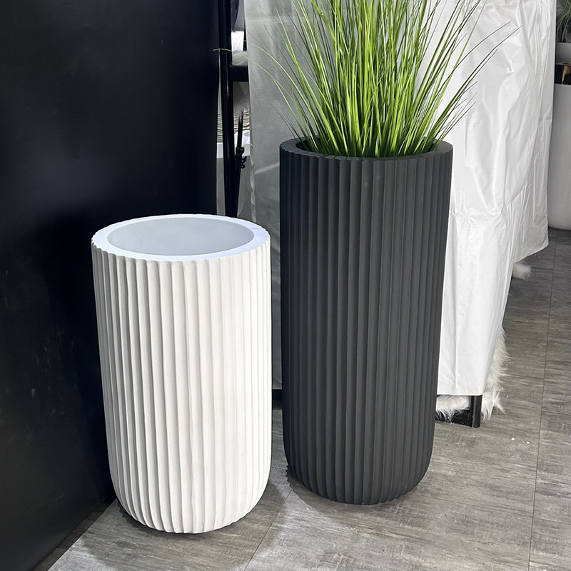A large floor-standing plant arrangement in a minimalist style beside the sofa in the living room, featuring a new matte black and white bright color vase