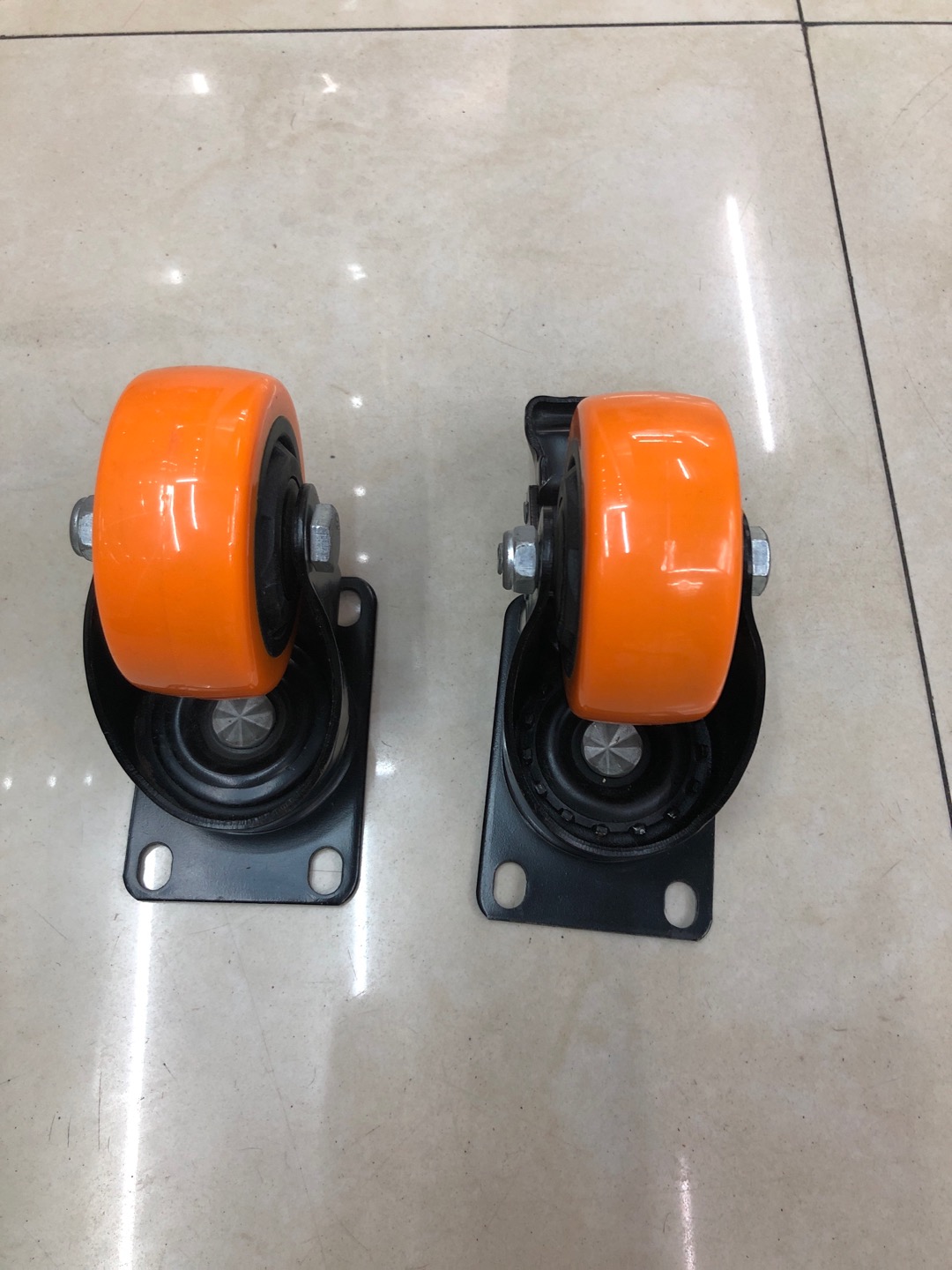 Medium-sized casters with perforated wheels, orange face and black core wheels details Picture