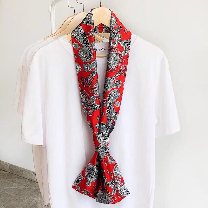 A vintage women's small neckerchief tied to a bag, a long and multi-functional scarf