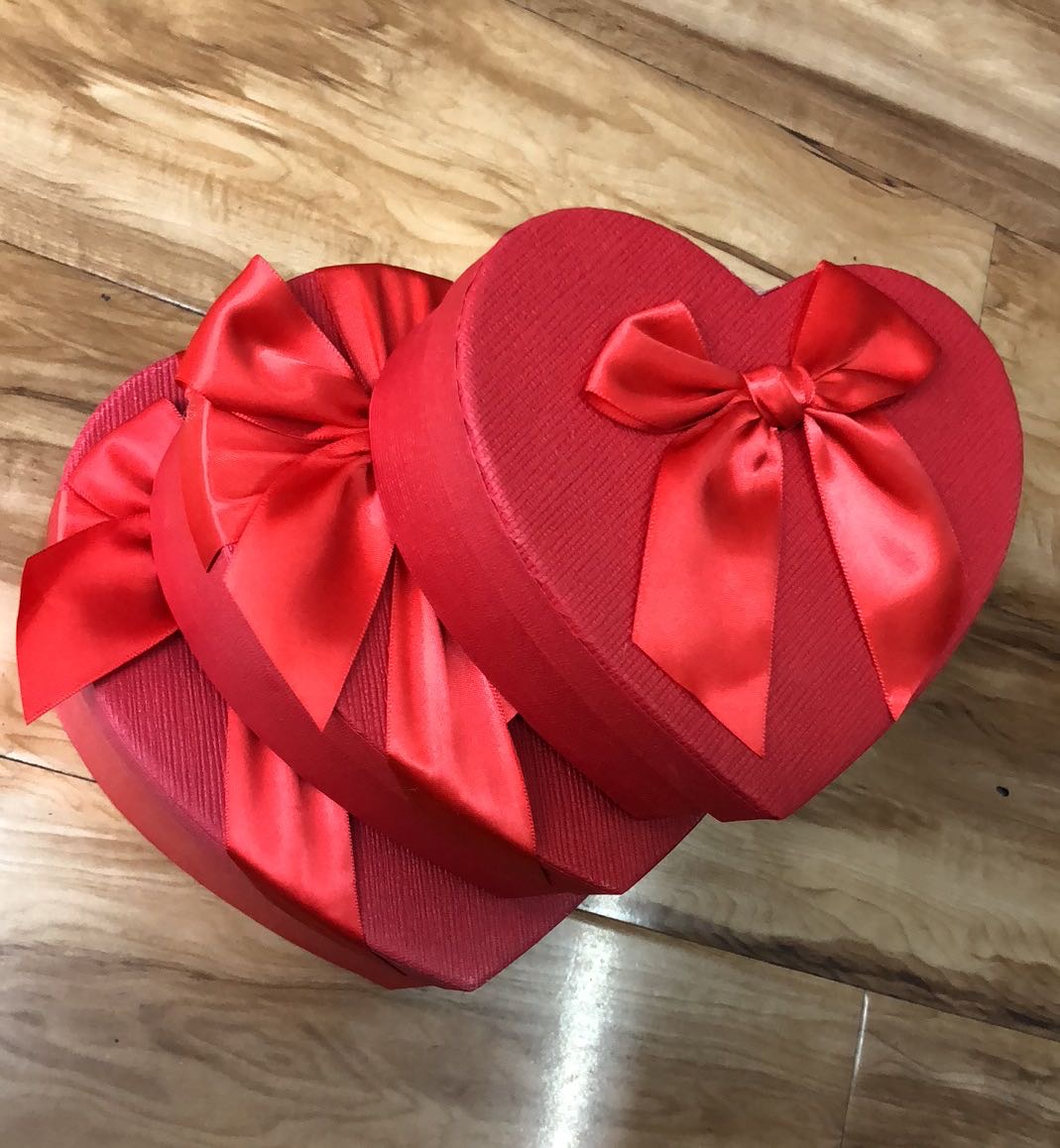 Multiple red heart-shaped gift boxes arranged creatively with flowers and ribbons