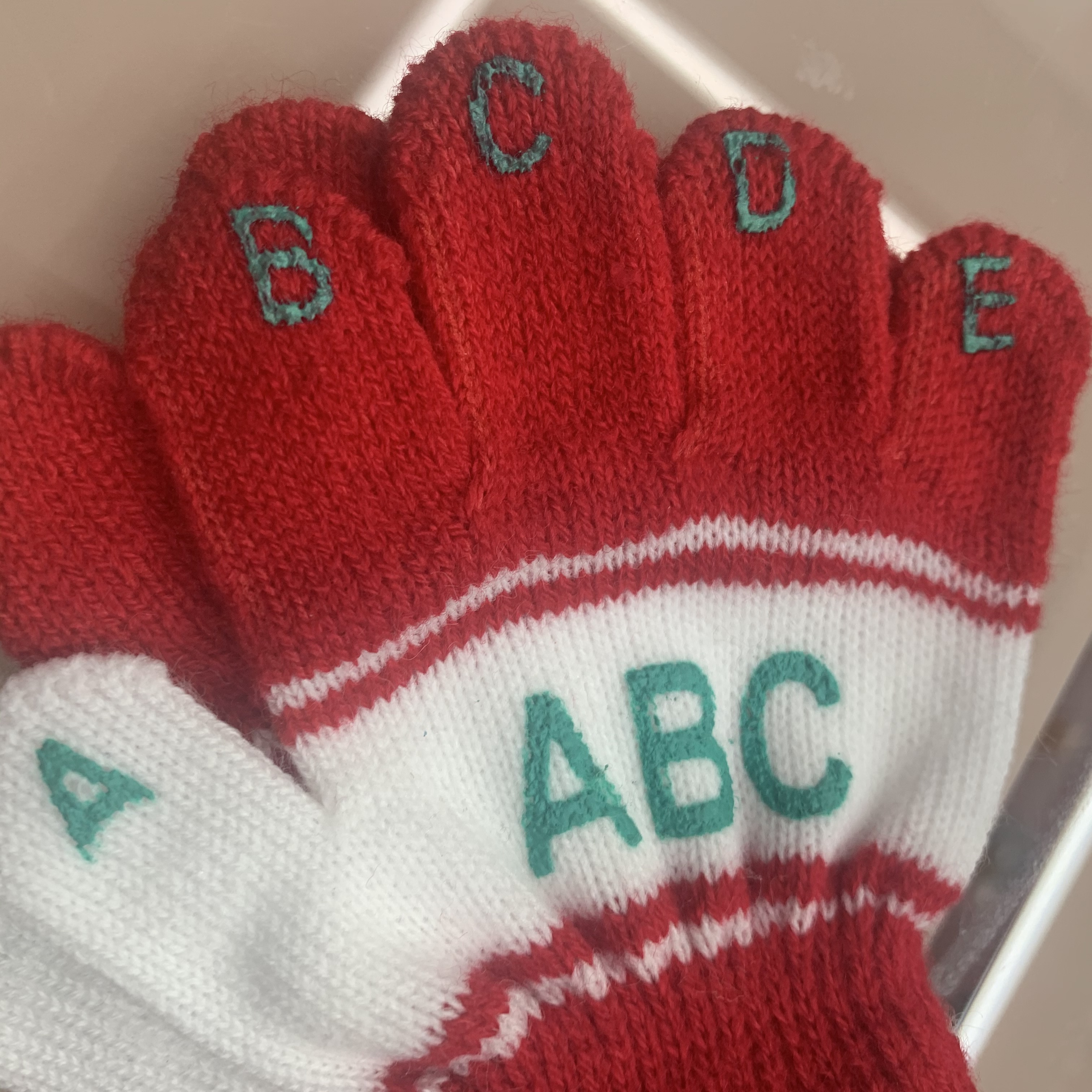 Close-up of child's hand wearing flexible five-finger winter glove while holding a pencil