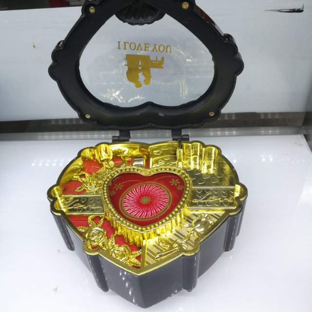 A retro music box in the shape of a heart box, half red and half gold details Picture